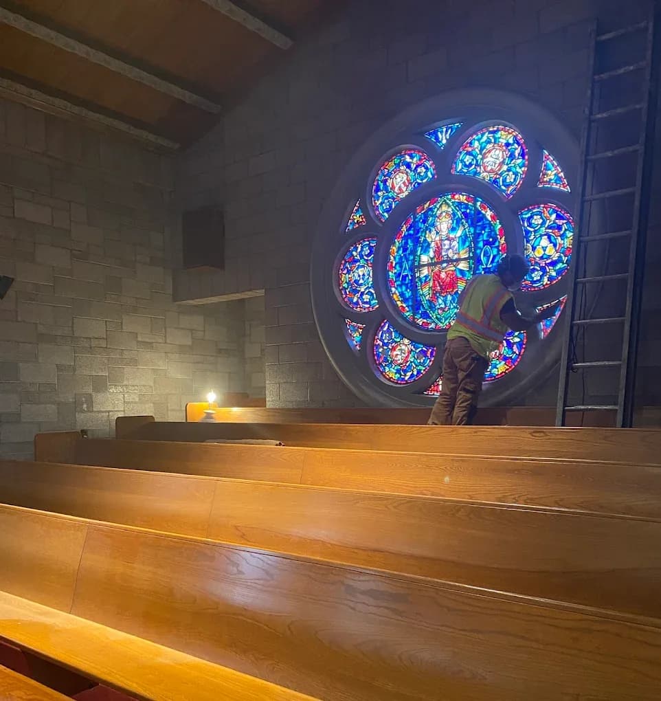 Church rose window with safety glass installation and warm sanctuary lighting
