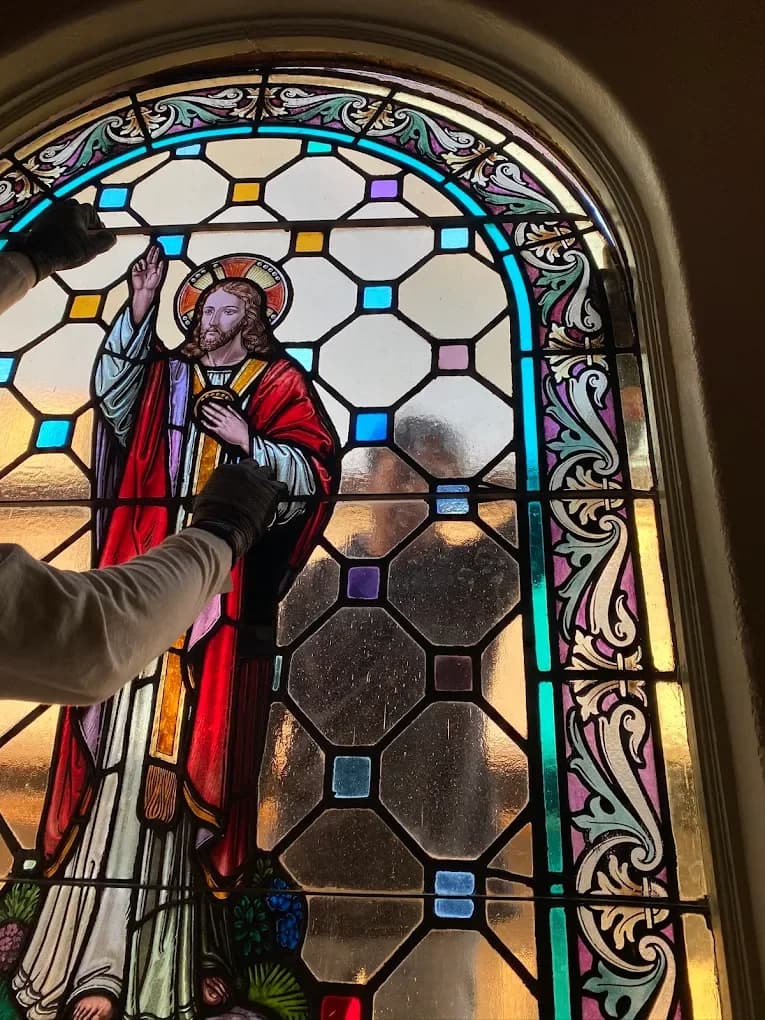 Close-up stained glass saint window repair with careful hand placement