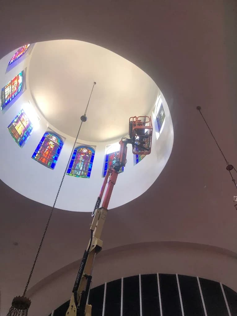 Tall church stained glass maintenance in a high interior wall opening